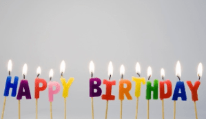 birthday candles in the shape of letters that spell Happy Birthday, all candles lit