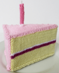 knitted slice of yellow cake with pink icing, raspberry filling, and a pink knitted birthday candle on top
