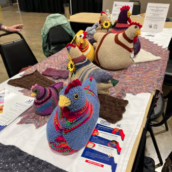 photo of a display table at the Oregon State Fair with seven Emotional Support Chickens in various colors, facing in different directions