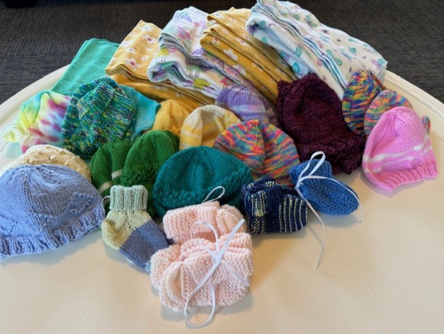 photo of knitted baby blankets, hats and booties in various colors