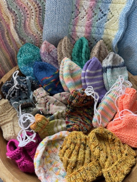 photo of knitted baby blankets, hats, and booties in many different colors