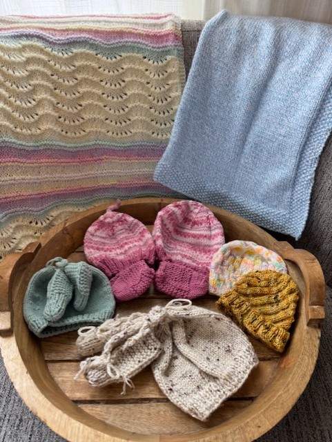 photo of knitted baby blankets, hats and booties in various colors